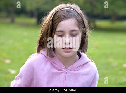 Une fille est au fond d'une pensée plaisante au milieu d'un parc le long d'une journée d'automne. Banque D'Images