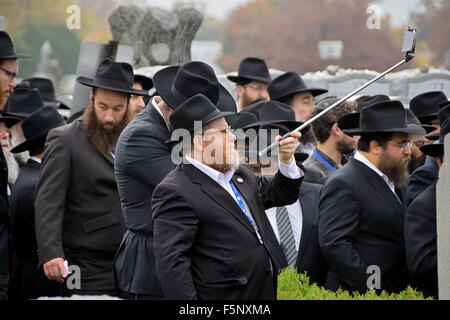 Un homme prend une photo de juifs religieux à l'Ohel à Cambria Heights en attente de dire une prière lors du Rebbe tombe. Banque D'Images