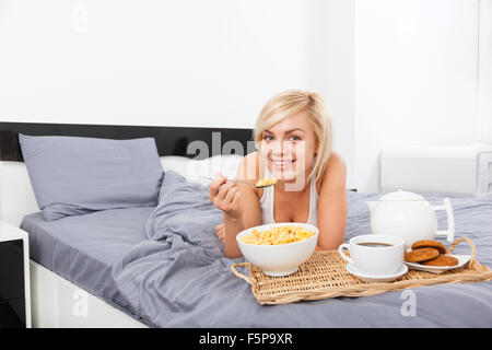 Petit-déjeuner au lit, young woman lying on bed Banque D'Images