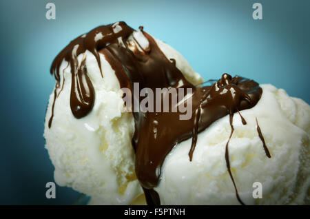 Dans la crème glacée avec une sauce au chocolat. .Gros plan sur fond bleu. Banque D'Images