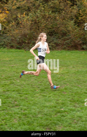 Jeune femme blonde runner enduite dans la pluie et la boue face à éléments en course cross-country avec pelouse de silencieux aux pieds Banque D'Images