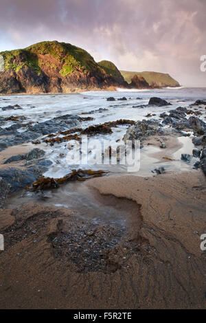 Les motifs sont laissés dans le sable de l'action des marées et les vagues comme les roches et les algues dentelées reculer sont laissés en Mouthwell beach. Banque D'Images