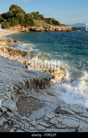 Les cailloux et les rochers sur la plage Kanoni et Bataria, Kassiopi, Corfou sont éclairés avec la lumière du lever du soleil orange Stong. Banque D'Images