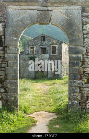 Une arcade vieux de la vieille Perithia, Palaia Peritheia, Corfou, Grèce, avec un bâtiment abandonné dans l'arrière-plan. Banque D'Images