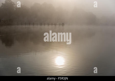 Le soleil commence à brûler un matin d'automne mist off Lake Windermere Banque D'Images