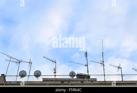 Antennes TV et antenne parabolique sur le toit contre ciel bleu. Banque D'Images