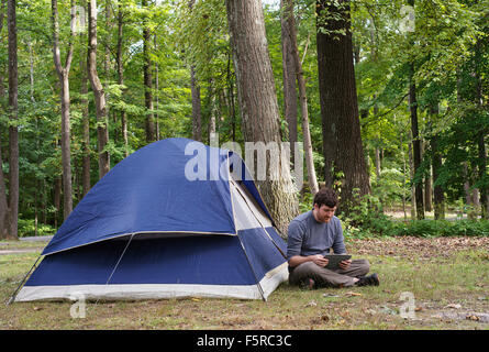 Un homme assis dans la nature dans les Catskills lire un ipad. Banque D'Images