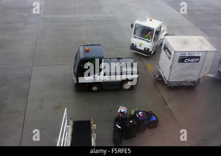 Les véhicules de manutention des bagages de l'aéroport sur le sol à l'aéroport d'Heathrow au Royaume-Uni. Banque D'Images