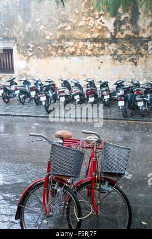 Vieille ville de Hoi An au Vietnam. Saison des pluies et de fortes pluies dans la ville. Hôtel des vélos et scooters garés dans la rue. Banque D'Images