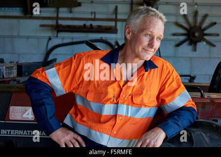 Agriculteur dans son hangar à côté de son tracteur Banque D'Images