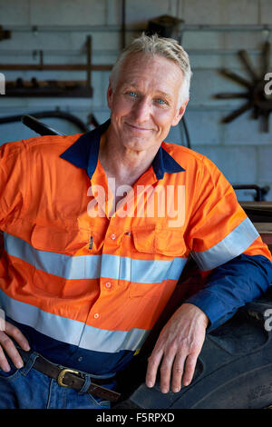 Portrait d'un agriculteur de chiffons de sécurité à côté de son tracteur Banque D'Images