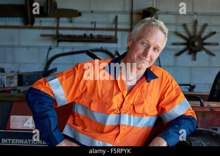 Portrait d'un agriculteur de chiffons de sécurité à côté de son tracteur Banque D'Images