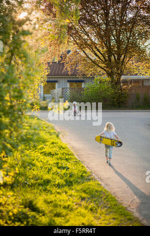 La Suède, Vastergotland, Lerum, Girl (6-7) walking to boy (8-9) avec skateboard