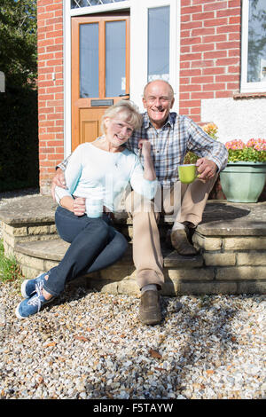 Senior Couple Sitting Outside House avec tasse de café Banque D'Images