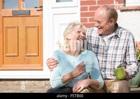 Senior Couple Sitting Outside House avec tasse de café Banque D'Images