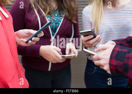 Groupe d'Adolescents Partager Message texte sur les téléphones mobiles Banque D'Images