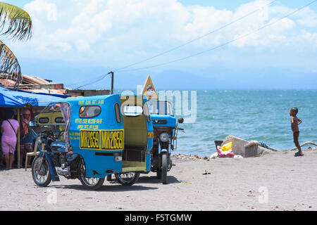 Deux cyclos garés à la plage dans la ville de General Santos, la ville la plus au sud des Philippines. Banque D'Images