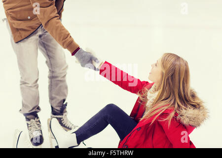 L'homme aide les femmes à se soulever sur patinoire Banque D'Images