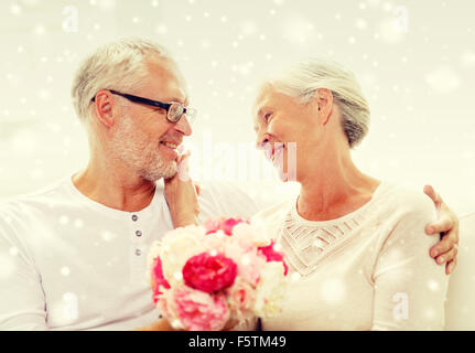 Happy senior couple avec bouquet de fleurs à la maison Banque D'Images