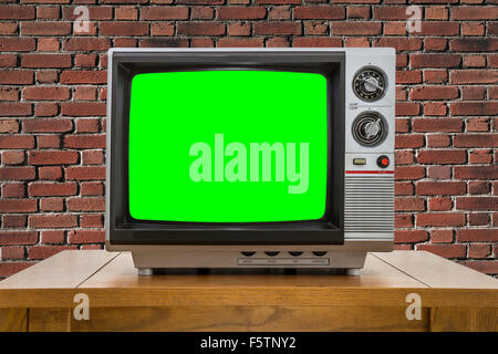 Vintage télévision portative avec mur de brique rouge et vert chroma key. Banque D'Images