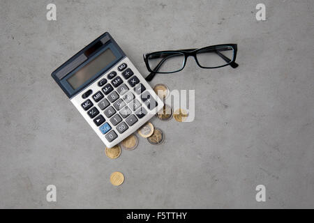 Calculatrice, les lunettes et les pièces en euros sur table Banque D'Images