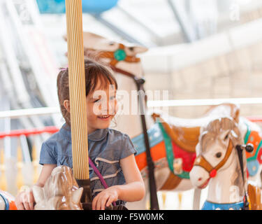 Young Girl riding carousel horse au amusement park Banque D'Images