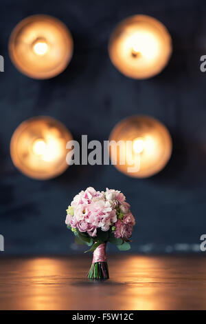 Bouquet de mariée sur un fond de lumière sur le plancher en bois dans la réflexion de la lumière Banque D'Images