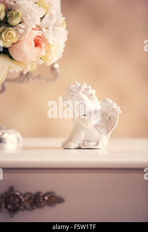 Statue d'un ange et un bouquet sur la commode dans l'intérieur Banque D'Images