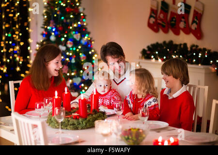 Grande famille avec trois enfants célébrer Noël à la maison. Dîner de fête à cheminée et arbre de Noël. Parent et enfant de manger Banque D'Images