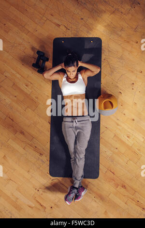 Fit young woman lying on exercise mat faisant des exercices de l'estomac. Vue aérienne de femmes à la salle de sport Banque D'Images