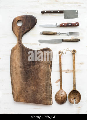 Cuisine-ware. Vieille planche rustique faite de bois de noyer, couteaux, fourchettes et cuillères à salade sur un fond blanc, vue du dessus Banque D'Images