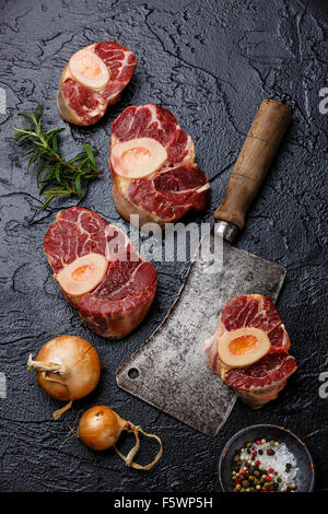 Frais de matières premières et de la queue de veau coupe croisée pour la fabrication d'ingrédients Osso Buco sur fond noir avec le couperet à viande Banque D'Images