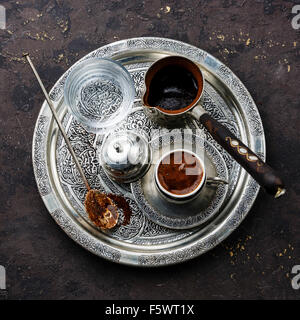 Le café turc dans la région de coffee pot et l'eau froide sur le plateau d'argent sur fond noir en noir Banque D'Images