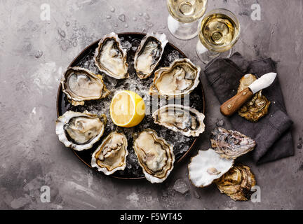 Ouvert les huîtres de Claire des amendes sur la plaque et le vin blanc sur fond de texture de béton gris Banque D'Images