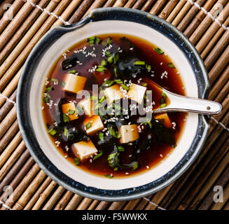 Soupe miso au tofu, algues et de sésame dans un bol sur fond de bambou Banque D'Images