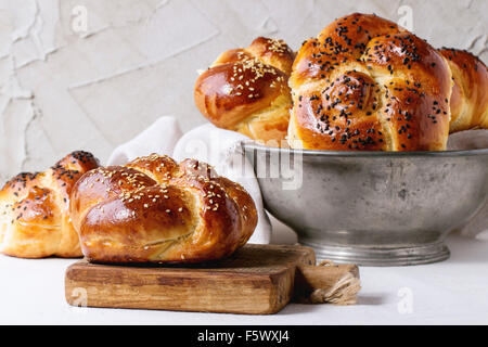 Tas de sweet pain challah sabbat ronde avec des graines de sésame noir et blanc vintage dans bol en métal et sur la petite planche à découper ove Banque D'Images