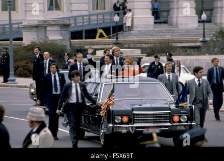 Washington, DC. USA 20 janvier 1981 Le président Ronald Reagan et Première dame Nancy Reagan se lever à travers le toit ouvrant de leur limousine forme aux foules qui tapissent les trottoirs de la capitale qu'il quitte pour le début de leur défilé inaugural. Des agents du Service secret de protection présidentielle détail promenade le long de la côté limousine. C'est considéré comme un honneur pour les membres de l'organisation des services secrets de l'État, de marcher dans tout le parcours. Certains de ces agents ont également marché le long du cercueil du président Reagan comme retournée au capitol le long de cette même route pour ses funérailles. Banque D'Images