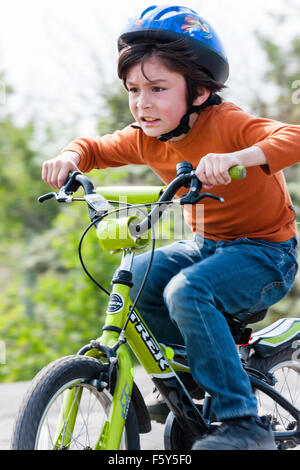 L'Angleterre. Caucasien enfant, garçon de 9 ans. Équitation vélo à vitesse avec blurrey arrière-plan. Expression du visage, déterminé la concentration. Banque D'Images