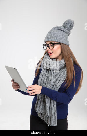 Portrait d'une jeune femme en tissu d'hiver using tablet computer isolé sur fond blanc Banque D'Images