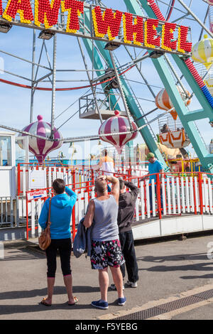 Les vacanciers dans une station fairground ride. Les gens qui regardent la roue géante à Pleasure Beach, Skegness, Lincolnshire, Angleterre, RU Banque D'Images