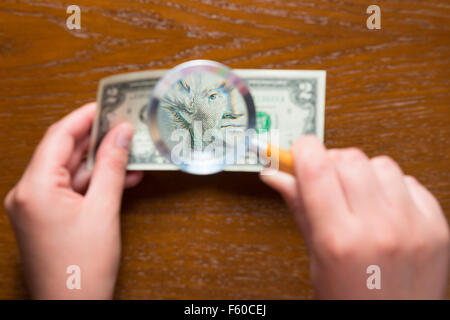 Lentille grossissante de femmes et deux dollars Banque D'Images