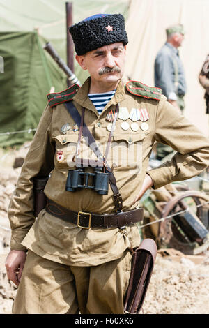 WW2 re-enactment. Office de cosaques russes qui pose, debout, des jumelles qui pendait au cou, face, hat cosaque. Banque D'Images