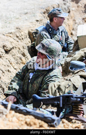 Seconde guerre mondiale re-enactment. Viewer en regardant deux Waffen SS soldats en tranchée avec mitrailleuse MG42 en premier plan. Banque D'Images