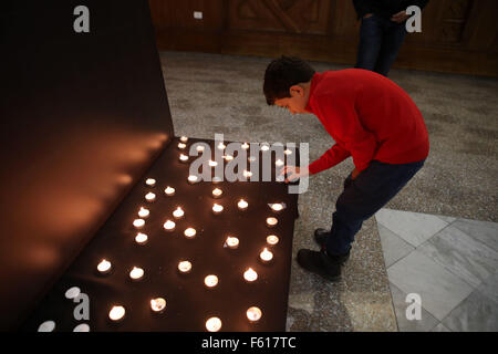 Ramallah, Cisjordanie, territoire palestinien. 10 Nov, 2015. Un garçon palestinien allume une bougie dans l'avant de la photo de la fin du leader palestinien Yasser Arafat pour marquer le 11e anniversaire de sa mort, à Ramallah Cultural Palace dans la ville de Ramallah, en Cisjordanie, le 10 novembre 2015 Crédit : Shadi Hatem/APA/Images/fil ZUMA Alamy Live News Banque D'Images