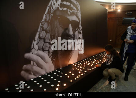 Ramallah, Cisjordanie, territoire palestinien. 10 Nov, 2015. Une femme palestinienne allume une bougie dans l'avant de la photo de la fin du leader palestinien Yasser Arafat pour marquer le 11e anniversaire de sa mort, à Ramallah Cultural Palace dans la ville de Ramallah, en Cisjordanie, le 10 novembre 2015 Crédit : Shadi Hatem/APA/Images/fil ZUMA Alamy Live News Banque D'Images