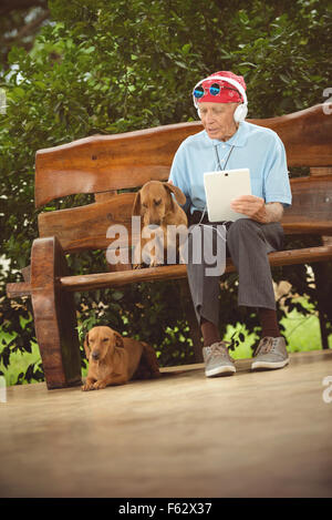 Un homme âgé avec bandana, lunettes et casque d'écoute, rock and roll sur la tablette. Banque D'Images