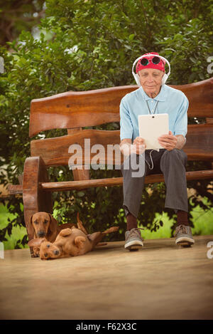 Un homme âgé avec bandana, lunettes et casque d'écoute, rock and roll sur la tablette. Banque D'Images