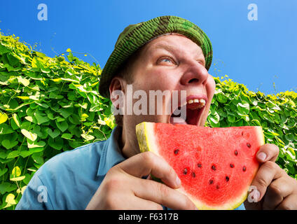 Bizarre man eating watermelon extérieur en été Banque D'Images