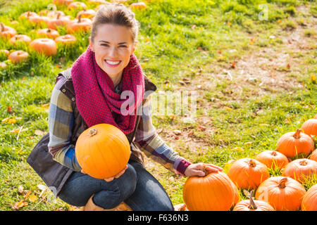 Portrait of smiling woman holding pumpkins sur la citrouille sur la ferme pendant la saison d'automne Banque D'Images