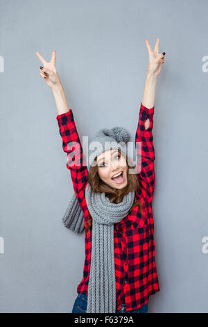 Portrait of a smiling woman showing signe de paix sur fond gris Banque D'Images